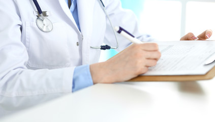 Female doctor using medical form on clipboard closeup.  Physicianat work in hospital or clinic. Healthcare, insurance and medicine concept 