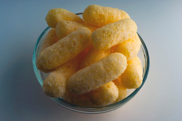 Corn Puffs in a Glass Bowl. Crunchy Flavored Puffed Snacks. Party, Movie Snacks.