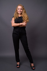 Young beautiful businesswoman with long wavy blond hair against 