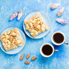 Two coffee cups, coffee grinder and apple pie on blue artistic background.