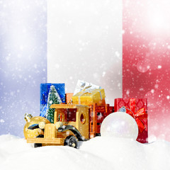 Christmas background.Toy truck with gifts, New Year fir, balls in the snowdrift and French flag