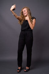 Young beautiful businesswoman with long wavy blond hair against 