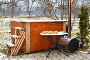 Wooden hot tub with stairs, chimney and heating stove in garden outdoor in winter day round snowy...