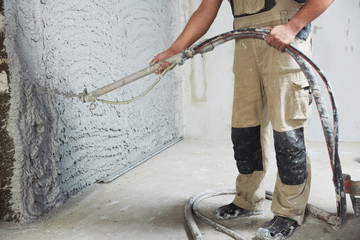 plastering the interior wall with an automatic spraying plaster pump machine - obrazy, fototapety, plakaty