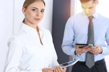 Obraz premium Beautiful blonde businesswoman using tablet pc while standing straight in a brightly lit office. Business concept