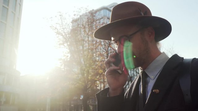 Busy businessman wear hat and sunglasses talking by two phones at the same time