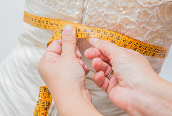seamstress take measuring to the bridal dress