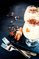 tiramisu in a glass decorated with coffee beans on a dark background
