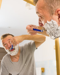 Guy shaving his beard in bathroom