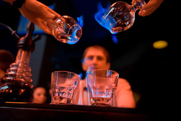 Bartender makes hot cocktail sambuca