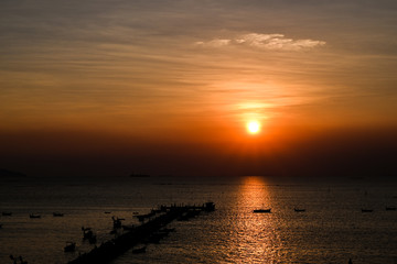 Sunset at the bridge by the sea with a boat surrounded.