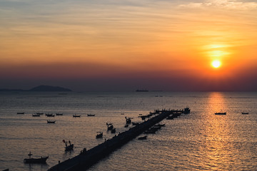 Sunset at the bridge by the sea with a boat surrounded.