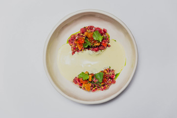 Meat tartare with mushrooms, sauce and greenery on a white plate