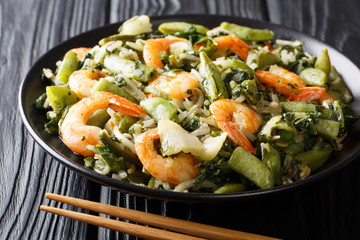 Delicious fried shrimp with spinach, soy sprouts, peas and pak choi closeup on a plate. horizontal
