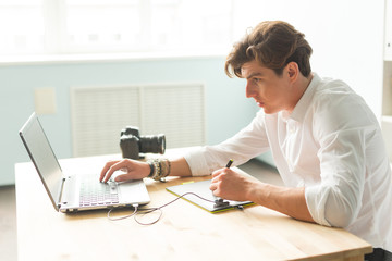 Business, technology, people concept - handsome man working with graphic tablet. He is an architector or multiplicator or designer