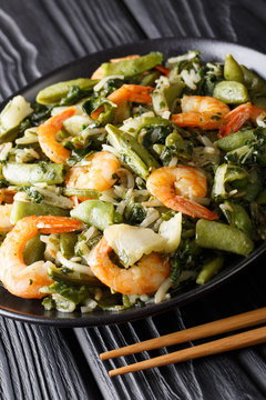 Stir fry of shrimp with spinach, soy sprouts, pea pods and  pak choi close-up. vertical