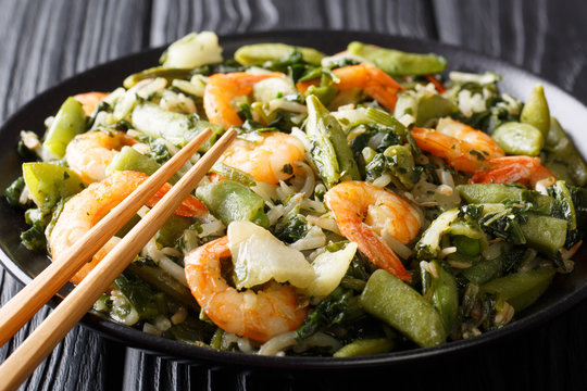 Delicious peeled king prawns with a refreshing mix or pak choi, spinach, soy beans and sugar snap peas closeup. horizontal