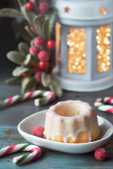 Close-up on bundt cake on rustic green table decorated with candy canes, berries and Christmas lights in lantern