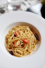 Spaghetti in a white plate with 3 tomatoes on top
