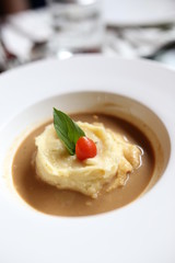 Mashed potatoes in gravy There are basil and tomato on top.