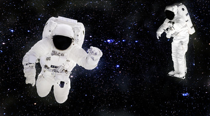 Astronauts in spacesuits floating in outer space. Spacemans at work. Starry dust. Elements of this image furnished by NASA