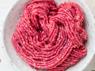 Mince beef, ground meat with ingredients for cooking on white wooden rustic table, top view,...