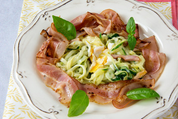 Scrambled eggs with zucchini, carbonara sauce and bacon