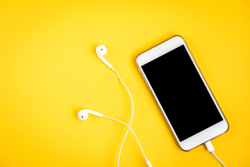 Mobile phone and headphones on yellow background - obrazy, fototapety, plakaty