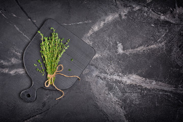 .Top view on fresh thyme green herb with twine rope on black wooden board