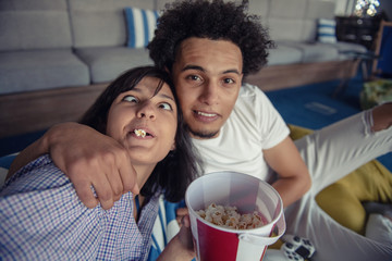 Playful young couple playing video games in their living room.