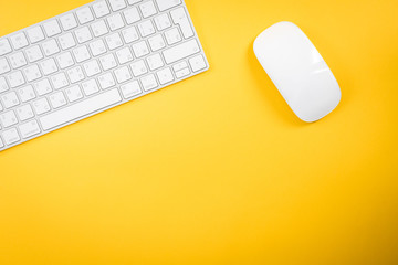 White keyboard and mouse on yellow background.