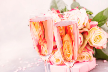 Bouquet of white and red roses, gift box, glasses with pink champagne for a pair of lovers for St. Valentines Day, gray background, selective focus