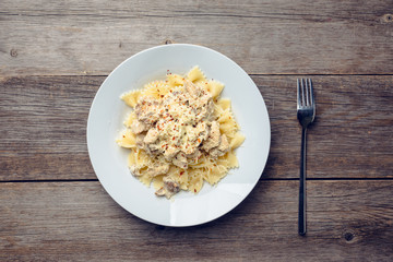 Fresh pasta with chicken, mushrooms and cheese on the rustic wooden background. Selective focus.