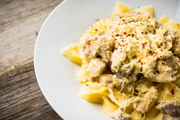 Fresh pasta with chicken, mushrooms and cheese on the rustic wooden background. Selective focus.