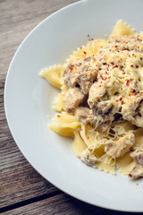 Fresh pasta with chicken, mushrooms and cheese on the rustic wooden background. Selective focus.