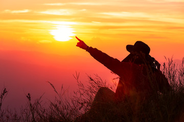Silhouette adventure traveler is finger pointing the sun