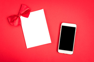 Mobile phone with greeting card on red background.
