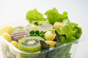 Salad of fresh vegetables and healthy grains ,In clear plastic box,On a white background