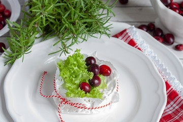 Camembert cheese decorated with cranberries and green salad