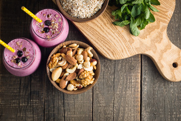 Fototapeta premium Glasses of berry smoothie with nuts, mint, blueberry, blackberry, raspberry, and yogurt on wooden table. Weight loss and diet concept. 