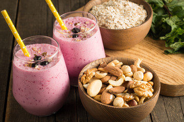 Glasses of berry smoothie with nuts, mint, blueberry, blackberry, raspberry, and yogurt on wooden table. Weight loss and diet concept. 