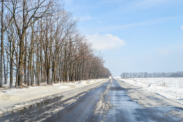 Driving on a snowy road in winter or early spring. View from the car window.