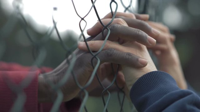 forbidden love. Black and white  man's hands touching through net