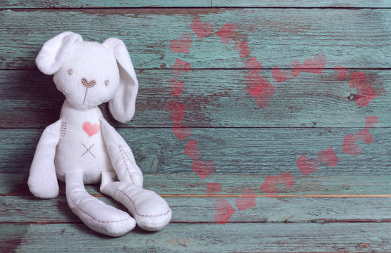 Valentin's day card with white bunny and heards on rustic wooden background.
