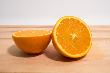 Fresh orange sliced in half on wooden board. Close up side view.