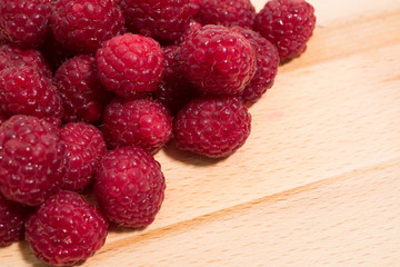 Heap of raspberry fruits on a natural wooden background.