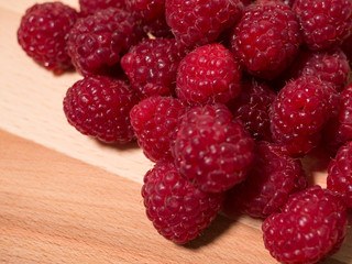 Pile of raspberries on natural wooden background. Close up.