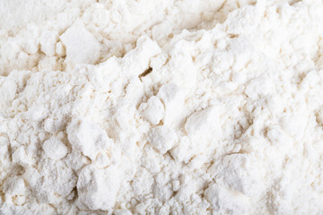 Pile of white wheat flour is scattered on an old worn cutting board