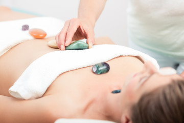 Obraz na płótnie Canvas Therapist placing therapeutic hot stones on woman's body in spa