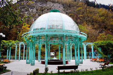 Fototapeta na wymiar The blue pavilion with mineral water located in old park in narrow gorge, adjecent to Borjomula river, Borjomi, Georgia, 